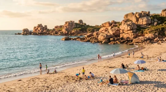 Plage familiale de Perros-Guirec en fin d'après-midi, avec familles sur le sable, enfants jouant près de l'eau, et formations caractéristiques de granit rose en arrière-plan sous lumière dorée